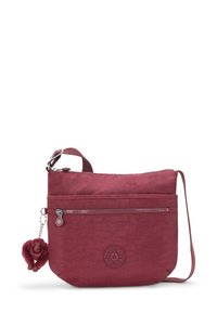 Crossbody bag in dark red fabric, featuring a textured surface, front zipper pocket, adjustable strap, and a monkey keychain accent.
