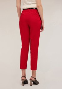 Rode slim-fit pantalons van een gladde stof, met een cropped lengte en twee achterzakken, gecombineerd met open teen hakken met een gestructureerd ontwerp.