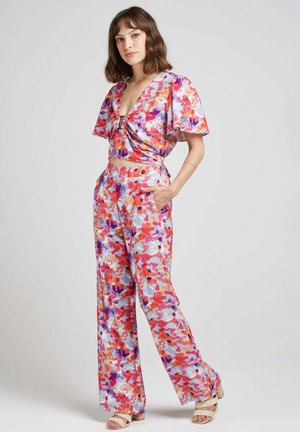 Ensemble floral deux pièces comprenant un crop top avec des manches courtes volantées et un pantalon large taille haute dans des nuances de rose, bleu et violet.