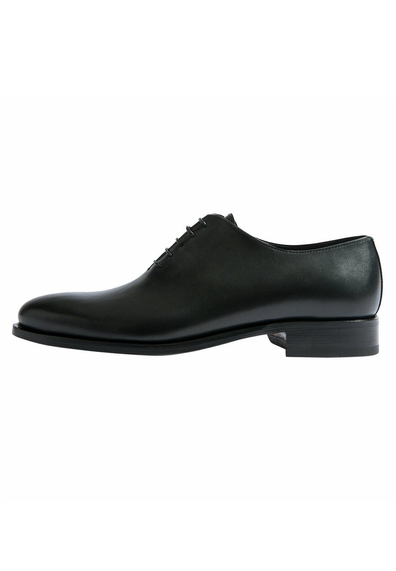 Chaussure habillée en cuir noir avec une texture lisse, bout arrondi, fermeture à lacets à l'avant et un petit talon empilé. Design simple sans motifs visibles.