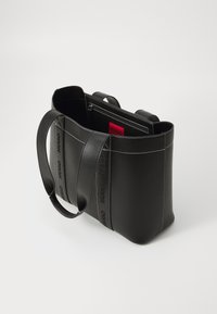 Svart läder tote-väska med kontrasterande vit sömnad, präglad logodetalj och dubbla topphandtag. Har en dragkedja inre ficka.