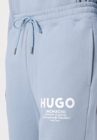 Lichtblauwe sweatpants met een elastische tailleband, trekkoord, zijzakken en witte bedrukte logo-details op het linkerbeen.