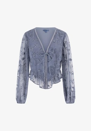 Világoskék, áttetsző blúz virágmintás hímzéssel, hosszú ujjakkal, fodros aljjal, V-nyakkal és megkötős záródással. Texturált anyag és aprólékos részletek jellemzik.