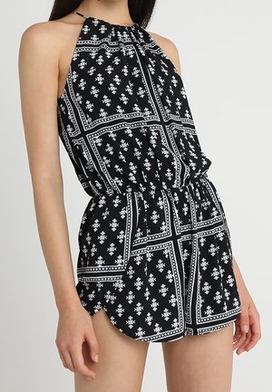 Czarny kombinezon na szyję z białymi kwiatowymi i geometrycznymi wzorami, elastyczna talia dla dopasowania, lekka tkanina i krótkie spodenki na dole.