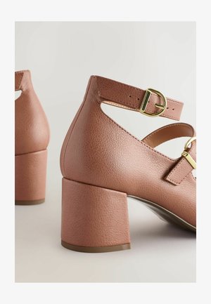 Roze leren blockhak schoenen met enkelbandje en gouden gesp. Beschikt over een uitgesneden ontwerp en een gestructureerde afwerking op het bovenmateriaal.