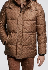 Brown quilted puffer jacket with geometric pattern, zip closure, and side pockets. Features a hood and a soft texture for warmth.