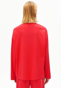 Rood shirt met lange mouwen van zachte stof, met een losse pasvorm, een ronde hals en minimale stikdetails aan de zoom en manchetten.