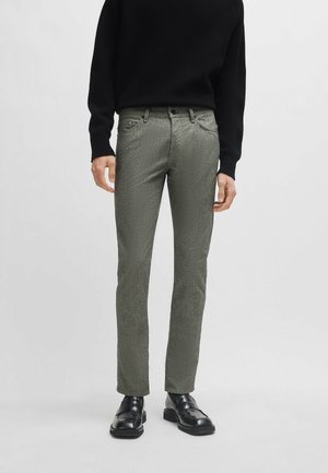 Groene textuurbroek met een slim fit, gemaakt van een geweven stof. Voorzien van een knopsluiting aan de voorkant en achterzakken. Gecombineerd met zwarte schoenen en een zwarte trui.