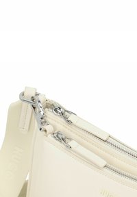 Borsa a spalla in pelle color crema con doppia cerniera, hardware argento e tracolla testurizzata. Presenta dettagli di marca sottili.