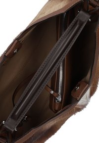 Bruine leren handtas met een zachte, gestructureerde bontafwerking. De binnenkant heeft een ritsvak en een bruine stofvoering, met zilveren hardware accenten.