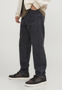 Tmavě modré volné džíny z denimu s měkkou texturou, vysokým pasem, zužujícími se nohavicemi a jemnými švy, doplněné černými teniskami.