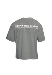 T-shirt gris à manches courtes avec texte blanc « ©DROPSIZE STUDIO (030) | Creative Visions - Authentic Design | EST 2020 » sur la partie supérieure du dos.