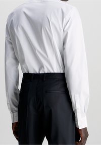 Witte lange mouwen shirt met een gladde textuur en knopenmanchetten, gecombineerd met zwarte broek met een getailleerde pasvorm en zijzakken.