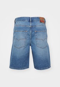 Gaiši zilas džinsu šortos ar nolietu izskatu ir divas aizmugures kabatas, redzamā šuvuma detaļas un zīmola ādas plāksne jostasvietā.