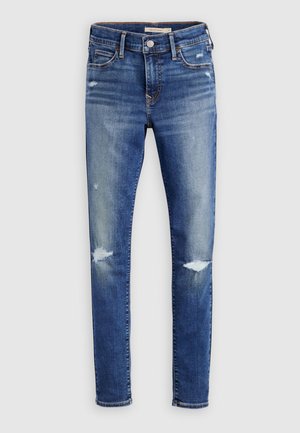 Blå skinny jeans med falmede og slidte områder, med forlommer, bæltestropper og knaplukning.