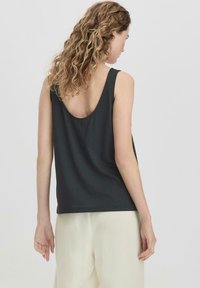 Zwarte mouwloze top met een brede ronde rug, gemaakt van zachte stof. Het heeft een losse pasvorm, eenvoudig ontwerp en rechte zoom.