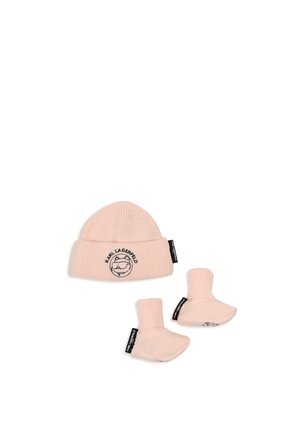 Cappellino da neonato lavorato a maglia rosa chiaro e scarpine abbinate con logo Karl Lagerfeld e etichette nere del marchio su sfondo bianco.