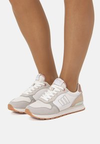 Sneakers bianche e grigie con un design testurizzato, caratterizzate da un accento rosa chiaro, lacci bianchi e suola in gomma marrone.