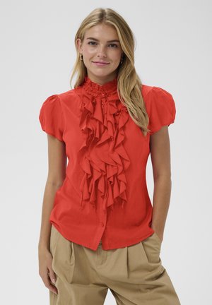 Bluza roșie cu mâneci scurte, având un design cu volane pe partea din față, închidere cu nasturi și guler înalt. Țesătură netedă cu ușoară strălucire.