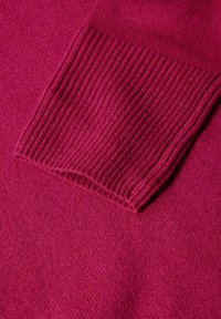 Magenta Pullover mit glatter Textur und geripptem Bündchen. Der Stoff ist weich und hat eine gleichmäßige Farbe.