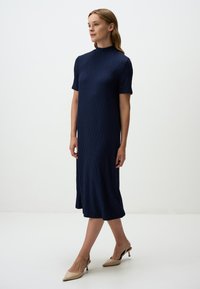 Abito midi blu navy in tessuto strutturato, con maniche corte e scollatura alta, abbinato a décolleté beige.