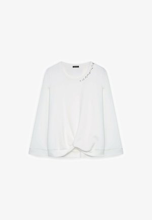Weißes Langarmoberteil mit rundem Ausschnitt und geknotetem Vorderteil. Mit dekorativen Strassverzierungen auf der Schulter.