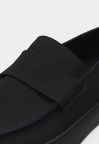 Mustad libisemisvastase tallaga mugavad kingad, mille eesosas on lai rihm ja ühtlane matt viimistlus.