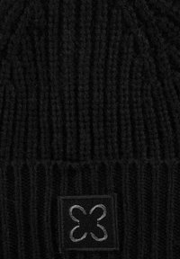 Zwarte gebreide beanie met verticale ribbelstructuur. Dit model heeft een zwart vierkant label met grijze borduurwerk van een ontwerp met vier lussen.