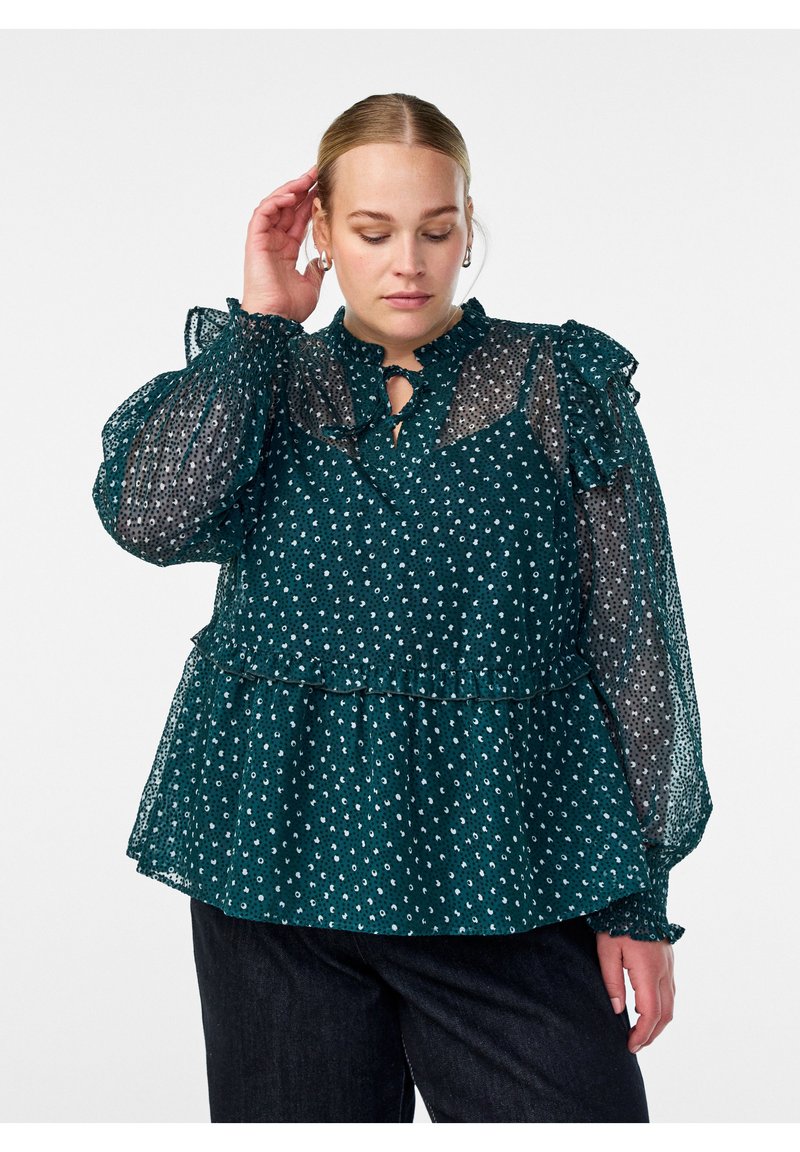 Türkise Bluse mit gerafftem Ausschnitt und Ärmeln, die ein transparenetes Überzug, ein Punktemuster und einen geschichteten Peplum-Saum zeigt. Verstellbare Bindegürtel.