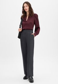 Burgundy blouse with a v-neckline and puffed sleeves, paired with gray pinstriped wide-leg trousers. Black platform shoes complete the outfit.