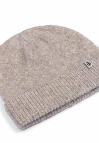 Light brown knitted beanie hat made of soft wool, featuring a ribbed cuff and a small sewn label on the side. Textured and flexible.