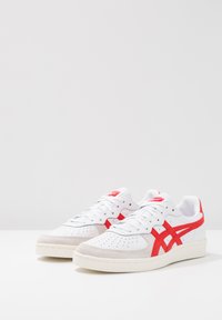 Vita sneakers med röda detaljer, med en slät läderöverdel, perforerat tåbox, vadderad krage och gummisula.