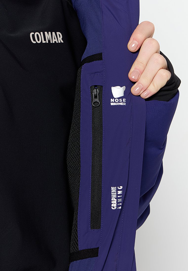 Giacca nera e viola scuro con tasca con zip, logo "Nose Warmer" e testo "Graphene Lining" sul braccio. Texture liscia.