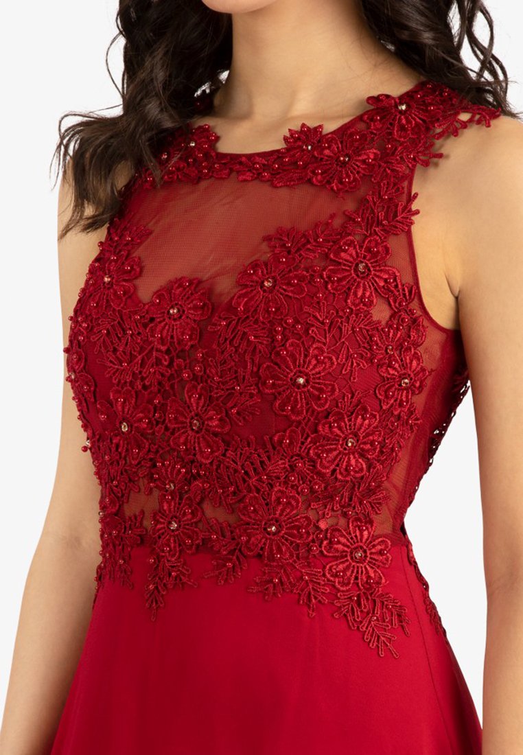 Ärmelloses rotes Kleid mit transparenter Netz-Oberseite, das mit aufwendigen floralen Spitzenapplikationen und Perlendetails verziert ist.