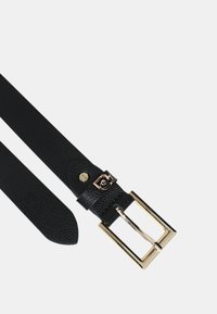 Cintura in pelle nera con texture liscia, dotata di una fibbia in metallo dorato e di un branding discreto su un'etichetta nera vicino alla fibbia.