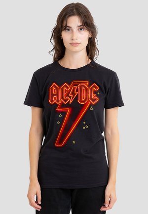 Black cotton t-shirt featuring a bold red AC/DC logo and lightning bolt design with yellow star accents. Short sleeves and round neckline.