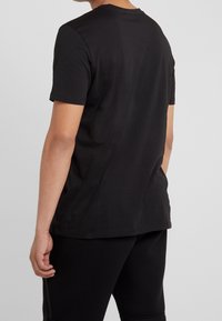 Sort T-shirt med korte ærmer og rund hals, lavet af glat bomuldsstof, med en afslappet pasform og uden sømme på skuldrene.