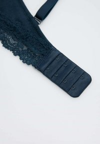 Tirante de sujetador azul oscuro con encaje; presenta un cierre de múltiples ganchos y tirante ajustable. Textura suave con intrincados detalles de encaje.