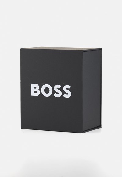 Boîte rectangulaire noire présentant le mot « BOSS » en lettres blanches grasses sur le devant, fabriquée en carton texturé avec une finition lisse.