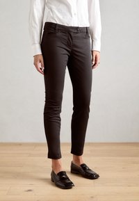 Czarne dopasowane spodnie wykonane z gładkiego materiału, z zapięciem na guzik, kieszeniami z przodu i tapered design, w połączeniu z błyszczącymi czarnymi loafersami.