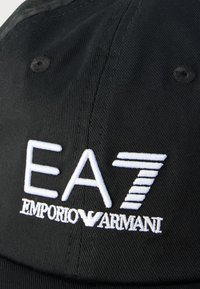 Fekete sapka, fehér hímzett "EA7 Emporio Armani" logóval. Az anyag texturált megjelenésű, szerkezetes formával.