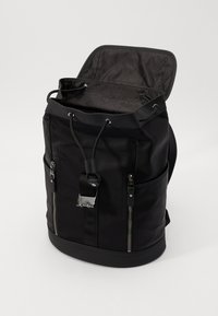 Black backpack made of durable fabric, featuring a top drawstring closure, front zip pockets, and silver-tone hardware accents.