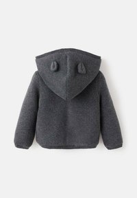 Szary sweter z dzianiny z kapturem, z dwoma zaokrąglonymi akcentami z tyłu, długimi rękawami i ribbrowanym dołem. Miękka faktura na całej powierzchni.