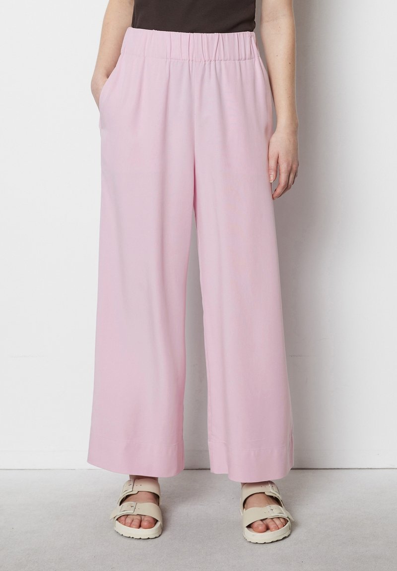 Pantaloni larghi rosa con cintura elastica, tasche laterali e un tessuto leggero e morbido. Rifiniti con un orlo dritto.
