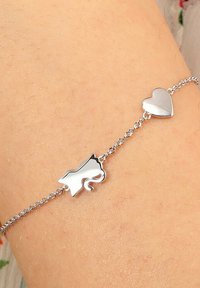 Bracciale in argento con silhouette di gatto e charm a forma di cuore. Finitura liscia e lucida con delicate maglie e design minimalista.