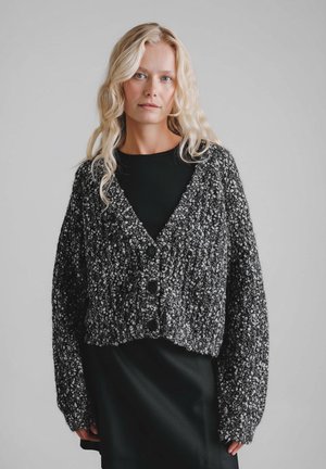 Czarno-biały melanżowy kardigan o fakturowanym splocie, z krótkim krojem, głębokim dekoltem w serek i dużymi czarnymi guzikami.