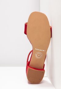 Sandale rouge avec semelle beige montrant la marque Pavement et la taille 37, positionnée debout contre un fond blanc d'angle.