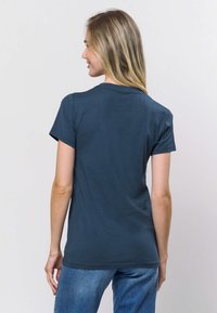 Tumši zila īsroku T-krekls ar apaļu kakla izgriezumu, izgatavots no mīksta auduma. Krekls ir ar vaļēju piegriezumu un gludu tekstūru.