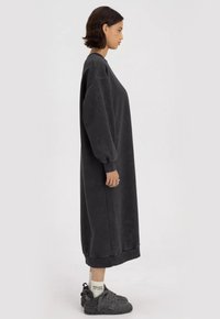 Oversized grijs sweatshirtjurk met lange mouwen en geribbelde manchetten, gemaakt van textuurstof, valt tot halverwege de kuit met een relaxte pasvorm.