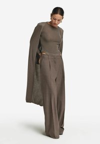Brun randig långärmad topp matchad med högmidjade, veckade vida byxor i en samordnande nyans, kompletterad med en lång, öppen cardigan.